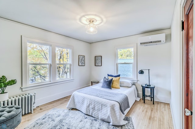 bedroom featuring a wall mounted air conditioner, light hardwood / wood-style flooring, and radiator