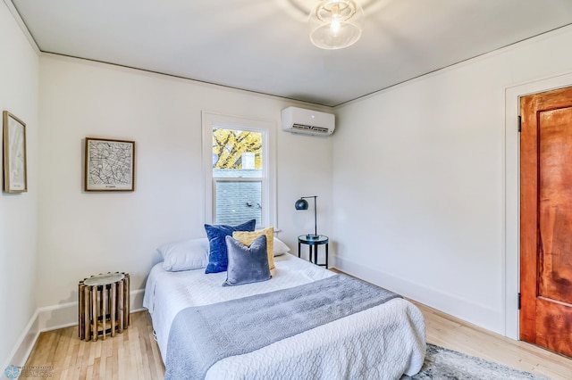 bedroom with an AC wall unit and light hardwood / wood-style flooring