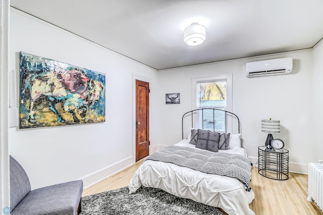 bedroom with radiator, light hardwood / wood-style flooring, and a wall unit AC