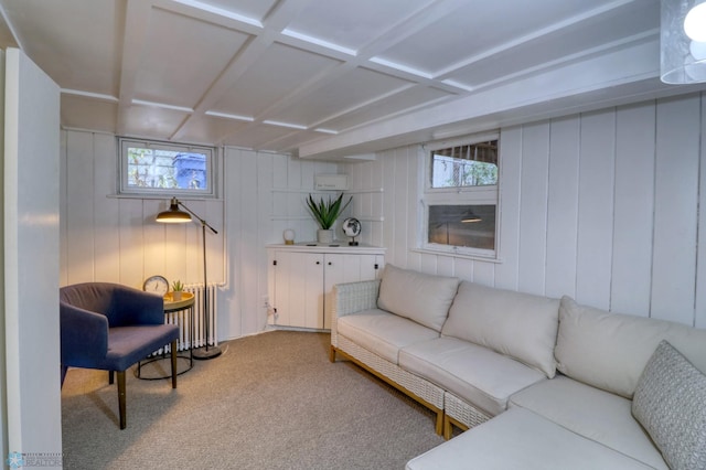 living room featuring coffered ceiling, light colored carpet, radiator heating unit, and wood walls