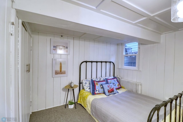 bedroom with carpet floors, radiator heating unit, and wood walls