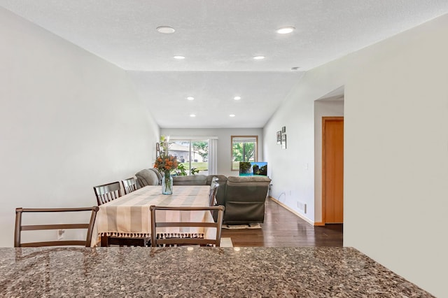 dining space featuring a textured ceiling, dark hardwood / wood-style floors, and vaulted ceiling