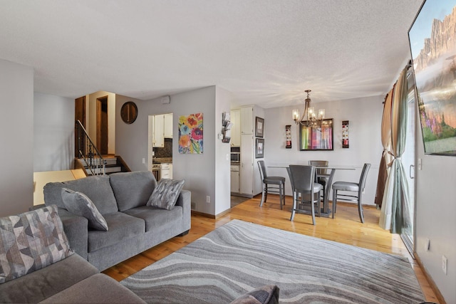 living room with an inviting chandelier, a textured ceiling, and light hardwood / wood-style flooring