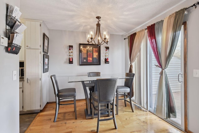 dining space featuring a chandelier, a textured ceiling, and light hardwood / wood-style floors