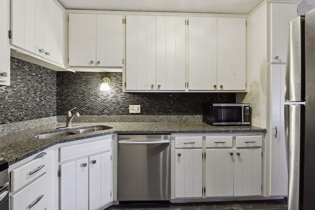 kitchen featuring sink, stainless steel appliances, dark stone counters, a textured ceiling, and white cabinets