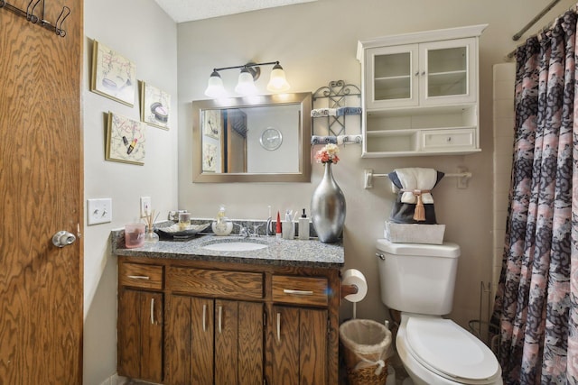 bathroom with vanity, toilet, a textured ceiling, and walk in shower