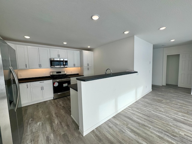 kitchen featuring kitchen peninsula, stainless steel appliances, and white cabinetry