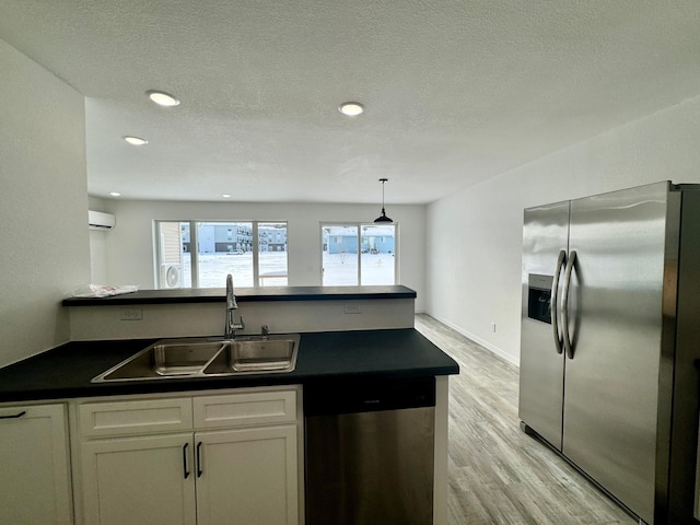 kitchen featuring pendant lighting, white cabinets, appliances with stainless steel finishes, sink, and a wall mounted AC