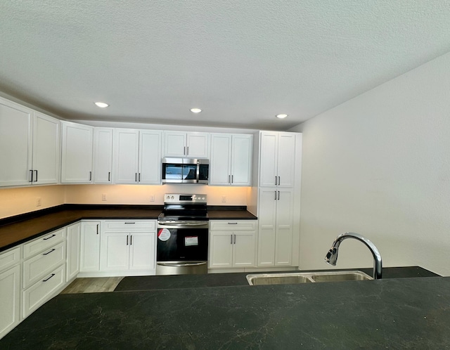 kitchen with a textured ceiling, stainless steel appliances, white cabinets, and sink