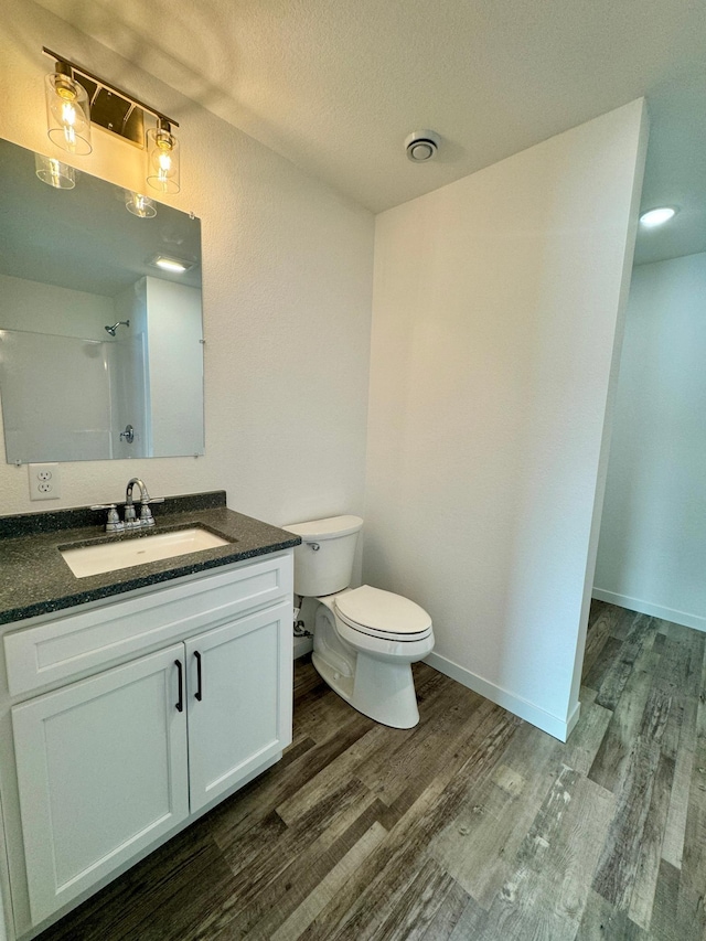 bathroom featuring a textured ceiling, vanity, toilet, walk in shower, and hardwood / wood-style flooring