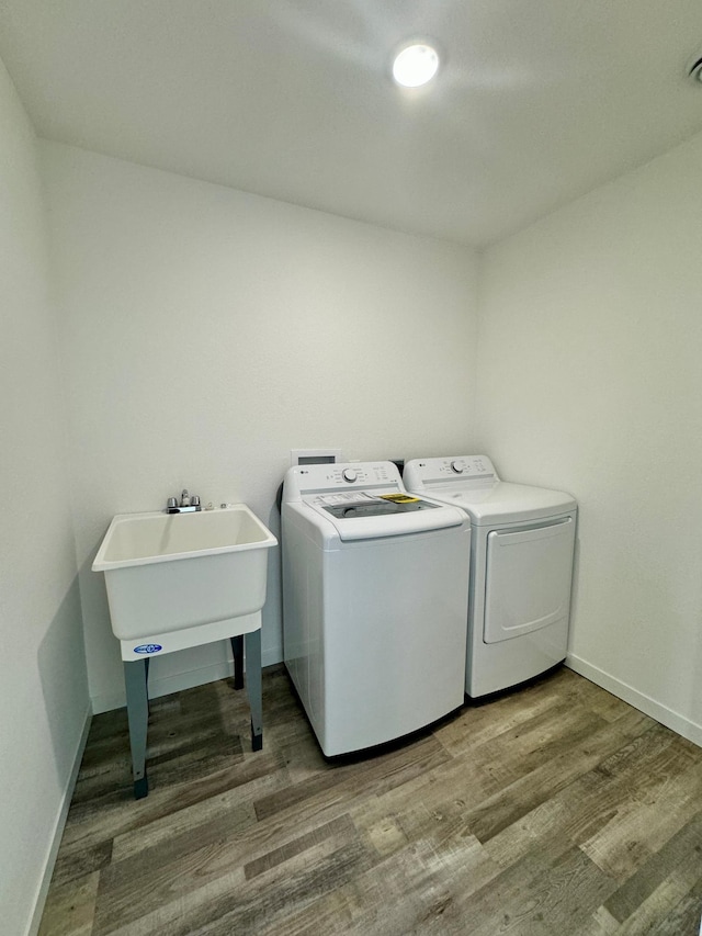 clothes washing area with wood-type flooring, sink, and separate washer and dryer