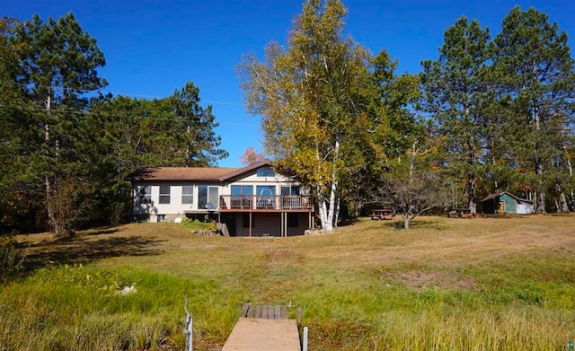 back of property featuring a deck and a lawn