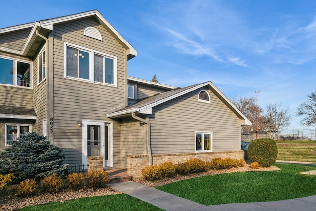 view of front of property with a front lawn, brick siding, and a shingled roof