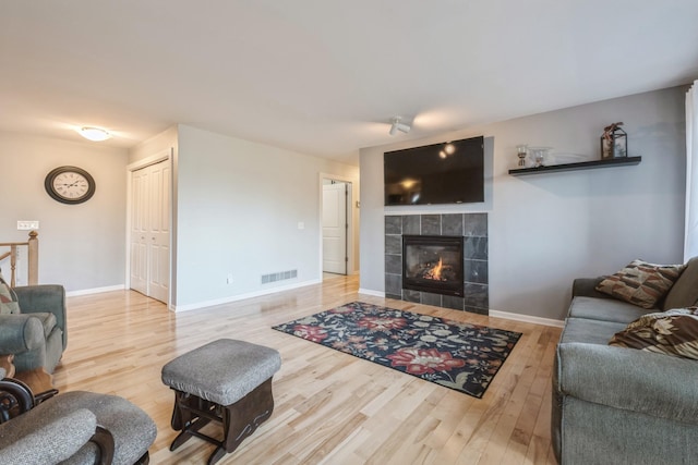 living room with baseboards, wood finished floors, visible vents, and a fireplace