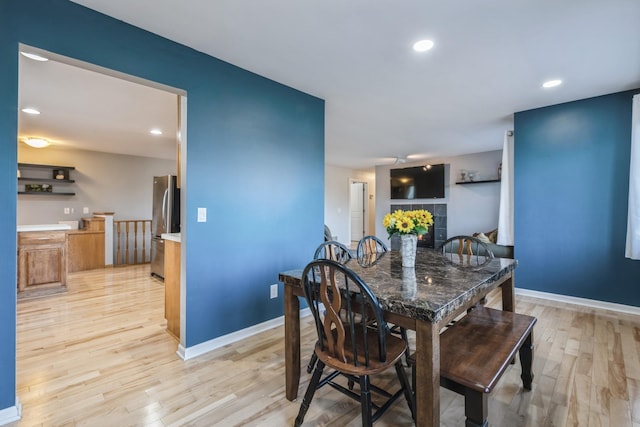dining room featuring light wood finished floors, baseboards, a fireplace, and recessed lighting