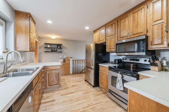 kitchen with stainless steel appliances, light countertops, a sink, and light wood-style floors