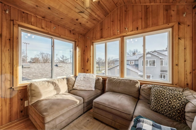 living area featuring lofted ceiling, wooden walls, and a healthy amount of sunlight