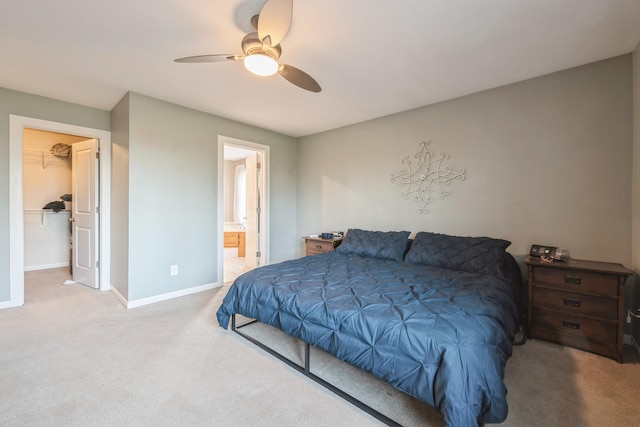 bedroom featuring a ceiling fan, a walk in closet, carpet floors, ensuite bath, and baseboards