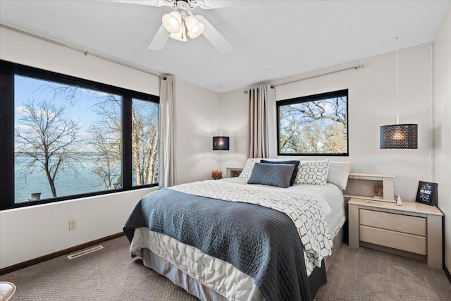 carpeted bedroom featuring a water view and ceiling fan