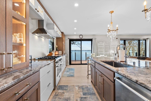 kitchen featuring sink, stainless steel appliances, a water view, light stone counters, and a chandelier