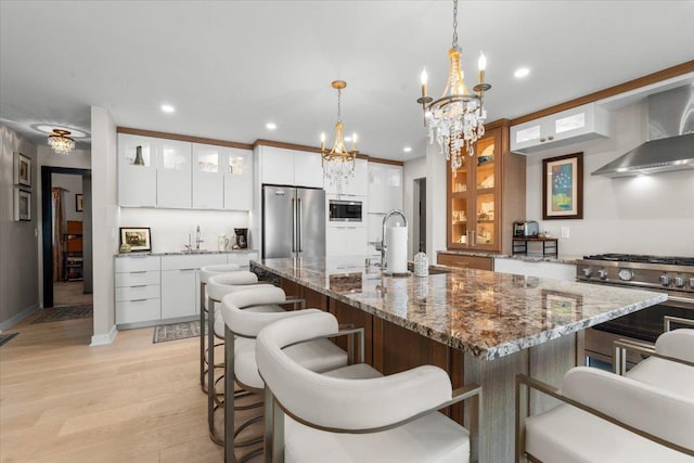 kitchen featuring pendant lighting, light hardwood / wood-style floors, white cabinetry, and stainless steel appliances