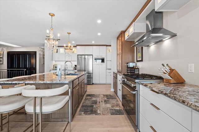 kitchen with white cabinets, appliances with stainless steel finishes, decorative light fixtures, sink, and ventilation hood