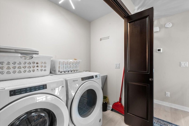 clothes washing area with light wood-type flooring and separate washer and dryer