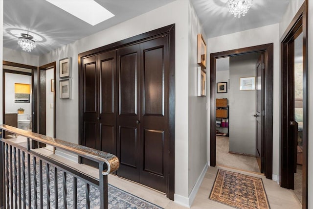 hallway featuring a skylight, light carpet, and a notable chandelier