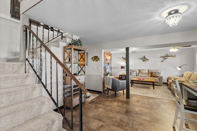 interior space with a textured ceiling and wooden walls