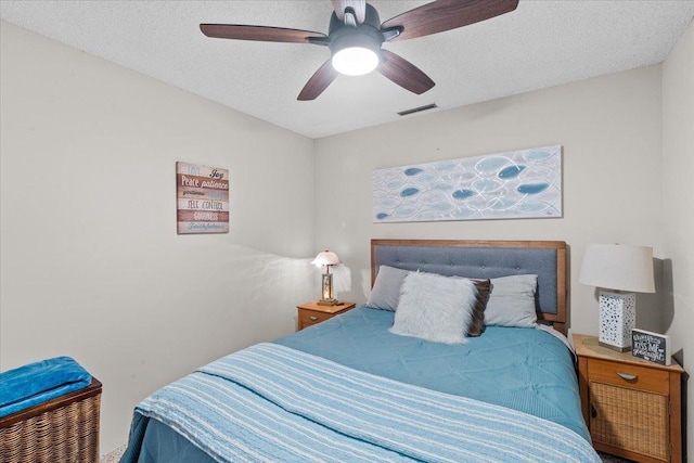 bedroom with ceiling fan and a textured ceiling