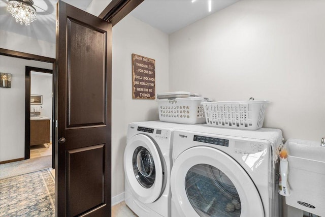 laundry room featuring light carpet, a sink, washing machine and dryer, baseboards, and laundry area