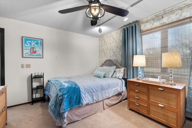 bedroom featuring baseboards, a textured ceiling, a ceiling fan, and light colored carpet