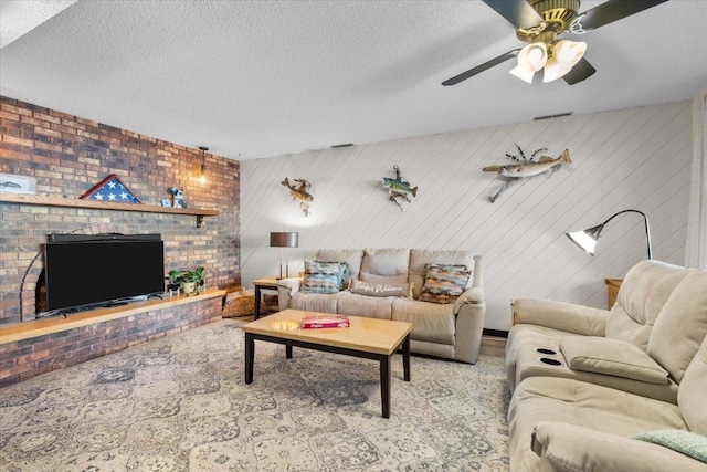 living area with visible vents, a ceiling fan, a brick fireplace, and a textured ceiling