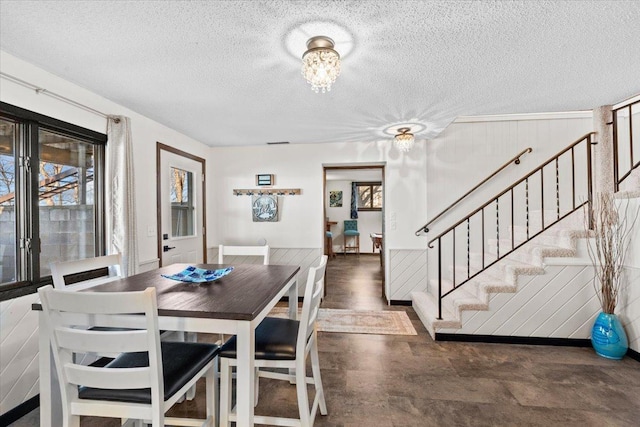 dining area with stairs, a textured ceiling, visible vents, and an inviting chandelier