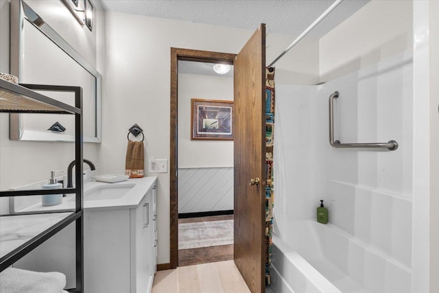 full bathroom with wood finished floors, vanity, a textured ceiling, and shower / tub combo with curtain