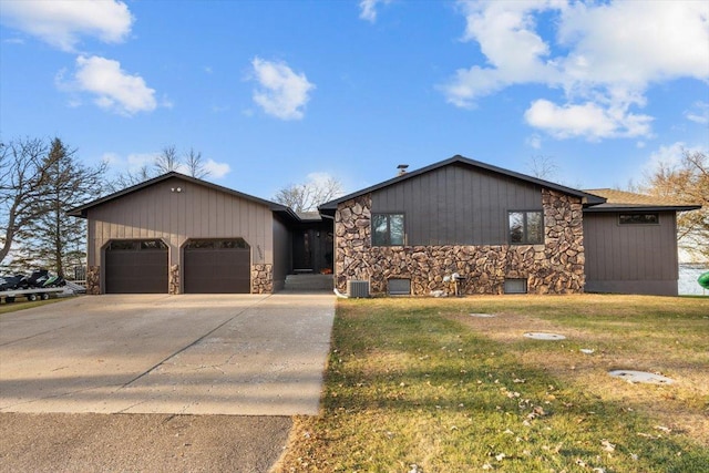 ranch-style home featuring a garage, a front lawn, stone siding, and concrete driveway