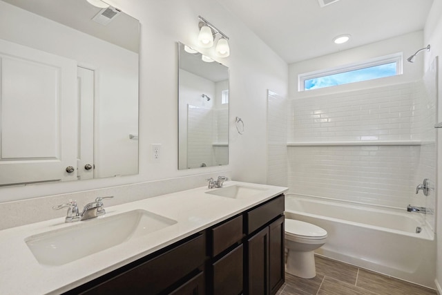 full bathroom with toilet, tiled shower / bath, and vanity