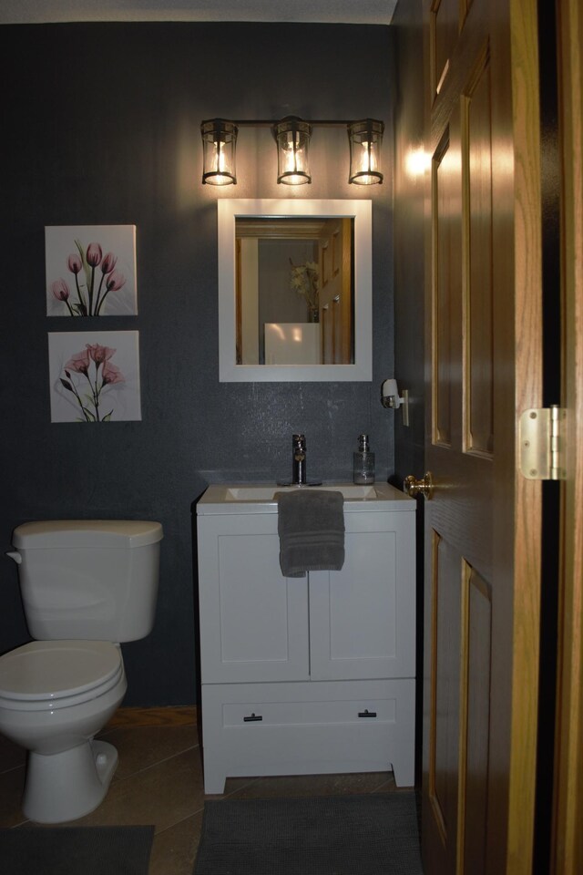 half bathroom with toilet, vanity, and tile patterned flooring