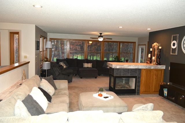 living area featuring a tiled fireplace, recessed lighting, light colored carpet, and a textured ceiling