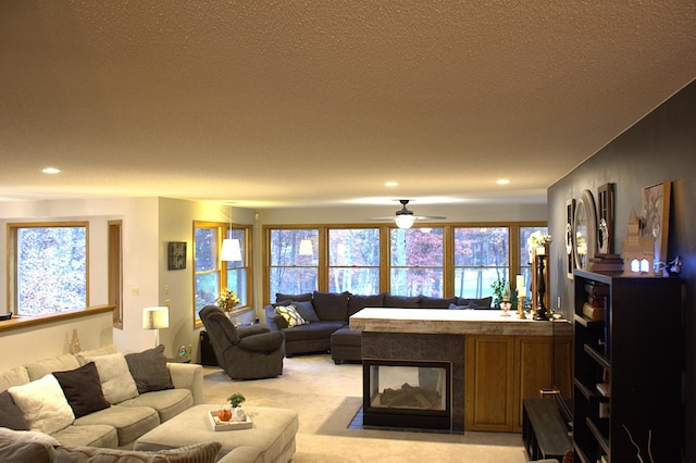 living room featuring light carpet, a ceiling fan, a textured ceiling, recessed lighting, and a multi sided fireplace