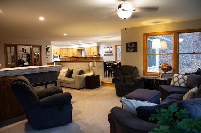 living room with light carpet, recessed lighting, and ceiling fan with notable chandelier