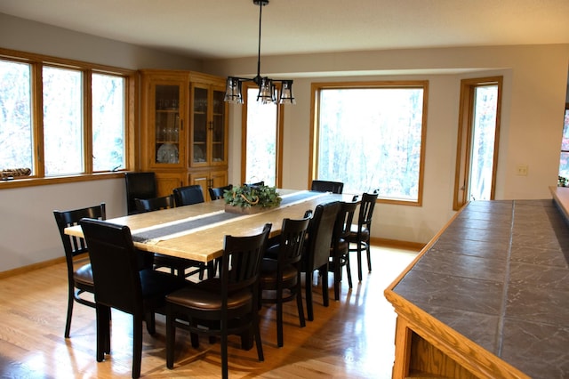 dining area featuring a notable chandelier, baseboards, and light wood-type flooring