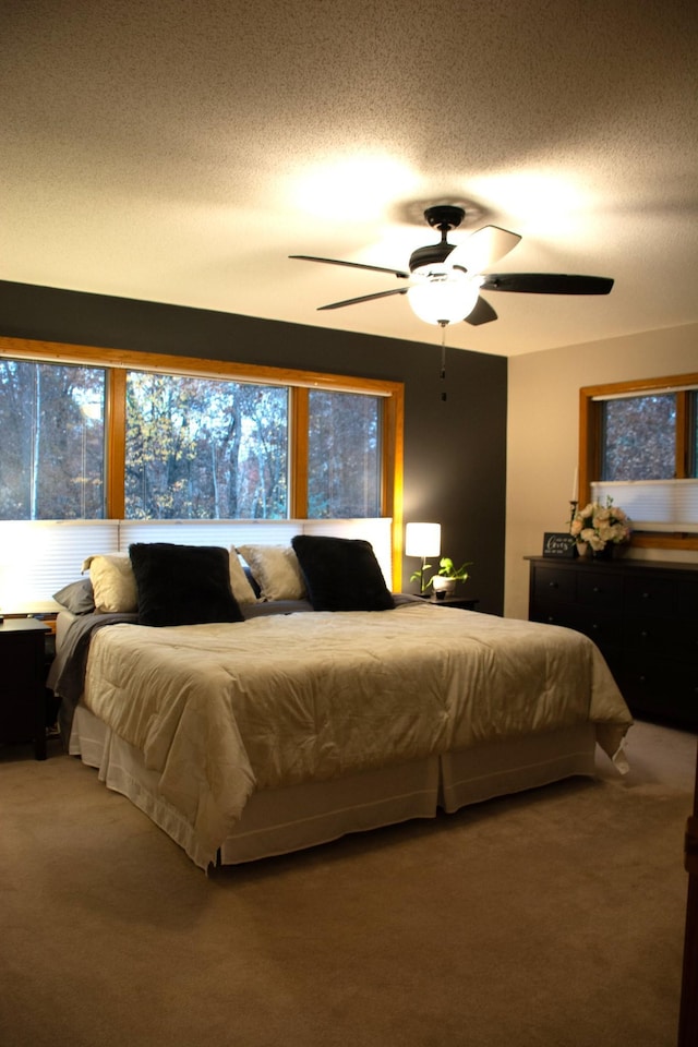 bedroom featuring ceiling fan, carpet flooring, and a textured ceiling