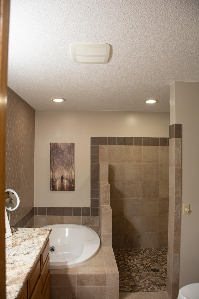 full bath with tiled shower, a textured ceiling, a bath, and vanity