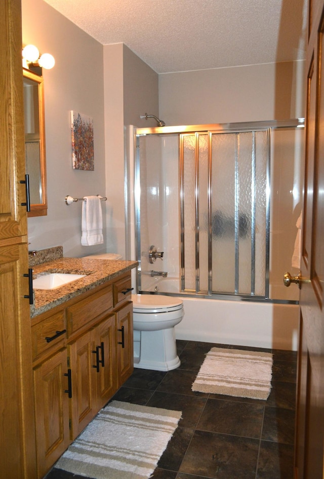 bathroom featuring combined bath / shower with glass door, a textured ceiling, vanity, and toilet