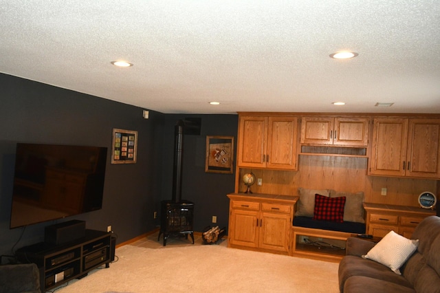 living room featuring recessed lighting, light carpet, a textured ceiling, and a wood stove