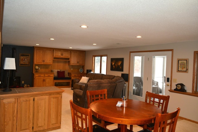 dining area with recessed lighting, light colored carpet, a wood stove, and a textured ceiling