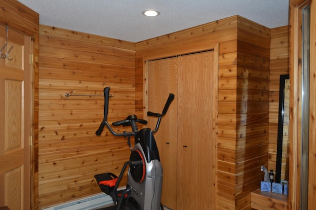 workout room with wood walls and a textured ceiling