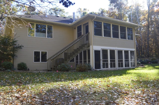 rear view of house featuring stairway, a yard, and a sunroom