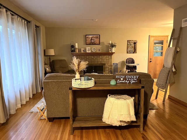 living room with a brick fireplace and hardwood / wood-style floors